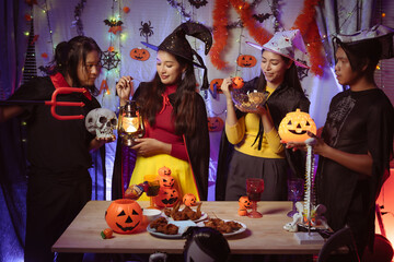 Asian man and woman celebrating Halloween, pumpkins at night, Halloween banner background for holiday activities.