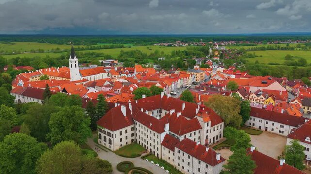 An aerial drone shot showcasing the magnificent Třeboň Castle and the charming historic town of Třeboň in South Bohemia, Czech Republic. The footage captures the distinctive red-tiled roofs, the promi