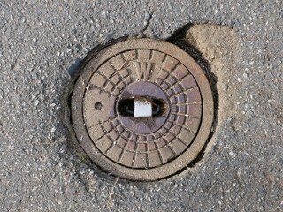 Metal water valve utility cover on asphalt road