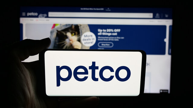 Stuttgart, Germany - 09-28-2025: Person holding cellphone with logo of US Petco Health and Wellness Company Inc. on screen in front of webpage. Focus on phone display.