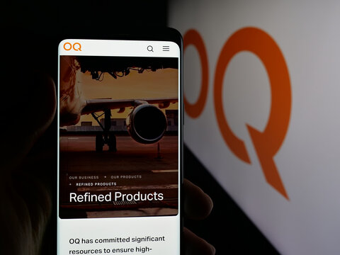 Stuttgart, Germany - 09-28-2025: Person holding smartphone with web page of Omani petroleum company OQ on screen in front of logo. Focus on center of phone display.