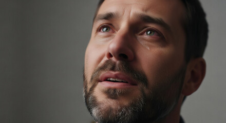 Fototapeta premium Close up of a man's face with tears streaming down his cheeks, conveying deep emotion and sorrow.