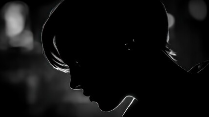 Silhouette of a person in profile with short hair against a blurred background