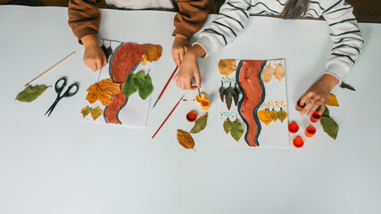 Children creating art with autumn leaves and paint