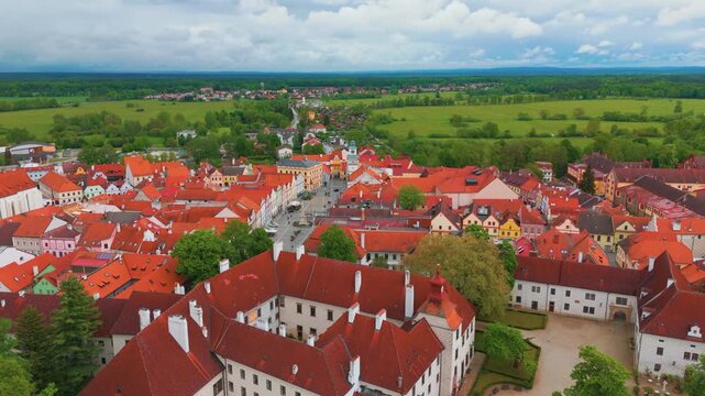 Dramatic aerial top view flight showcasing the historical town of Třeboň Wittingau in South Bohemia, Czech Republic, featuring its iconic castle, charming red roofed buildings, and surrounding lush la