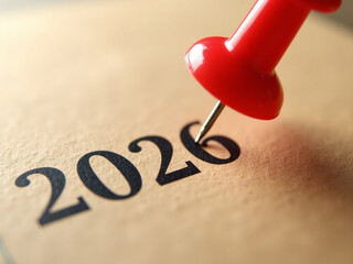 Macro Photography of Red Pushpin Indicating 2026 on Textured Brown Kraft Paper with Warm Lighting