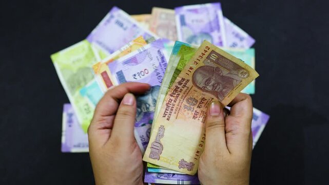 Indian rupee notes in hand, representing financial value and savings