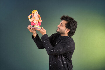 Happy young man holding and posing with Ganesha statue on the occasion of Ganesh Festival