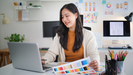 Female web designer developing mobile app layout, reviewing user interface mockups and design plans.