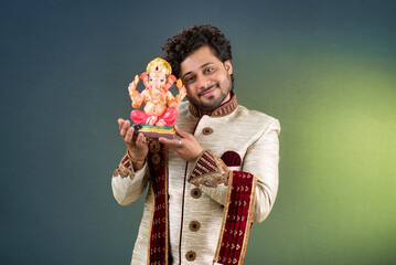 Happy young man holding and posing with Ganesha statue on the occasion of Ganesh Festival
