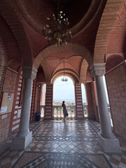 Woman standing in arched corridor with panoramic city view and traditional architecture