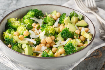green salad of broccoli, chickpeas, avocado, onion, and parsley with lemon oil, close-up in a bowl on a table. Horizontal