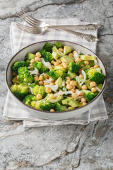 Vegan salad with broccoli, chickpeas, avocado, onions, and herbs close-up in a bowl on the table. Vertical