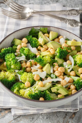 Broccoli, chickpea, avocado salad, a healthy and filling snack, close-up, in a bowl on the table. Vertical