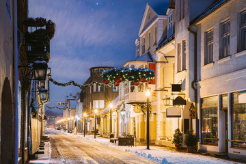 Fototapeta premium Parnu, Estonia. Night View Of Famous Ruutli Street With Old Buildings, Restaurants, Cafe, Hotels And Shops In Festive Evening Night Christmas Xmas New Year Illuminations