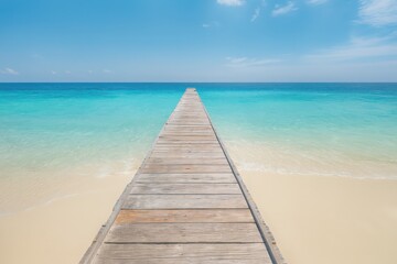 Fototapeta premium Wooden pier stretches out into turquoise ocean under a clear blue sky.