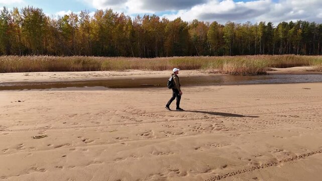 Futage 360 drone, an adult man with a backpack walks along the shore of the reservoir on an autumn day