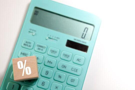 Calculator and wooden cube with percentage symbol on white background.