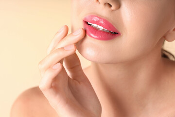 Fototapeta premium Woman with beautiful pink lipstick on her lips against beige background, macro view