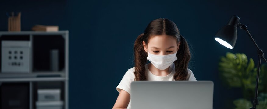 The girl wearing a face mask working on a laptop at a study desk - Powered by Adobe