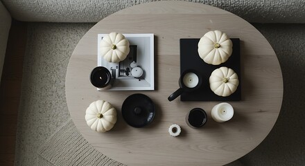 Minimalist autumn home decor flat lay with white pumpkins, candles, and modern accessories on a coffee table. Scandinavian hygge living concept