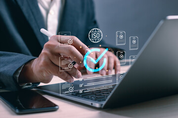 Businessman using digital pen on laptop for ISO certification and quality assurance process.Concept of international standard compliance, quality control, audit, best quality, service guarantee