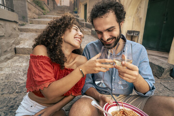 Happy couple eating pasta and toasting with wine in Italy. Romantic summer travel lifestyle and...