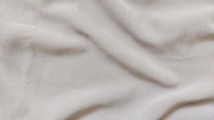 Fototapeta premium Wrinkled beige cloth background with soft cotton silk texture. Wavy fabric texture with smooth folds in cream color.