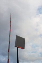 A motion sensor and barrier lift against a cloudy sky. Red light. Raised barrier.