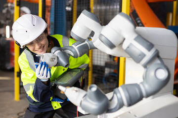 Female engineer operating collaborative robot in smart factory, smiling while adjusting robotic arm. Concept of cobot technology, automation, Industry 4.0, and human-robot interaction.