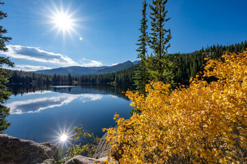 Sun shining on Bear Lake, a scenic trailhead and destination in Rocky Mountain National Park, Colorado, USA. Alpine lake landscape water reflection during fall foliage or autumn season