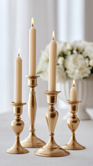 Four lit candles in golden holders with blurred white flowers