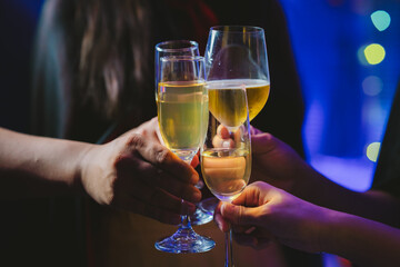 Close-up of people toasting with glasses of champagne or wine, celebrating together at a festive party with joyful atmosphere.