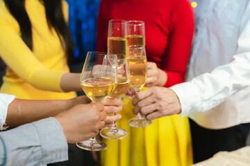 Group of friends clinking glasses of champagne together at a festive party, celebrating happiness and friendship with joyful smiles.