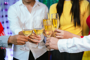 Group of friends clinking glasses of champagne together at a festive party, celebrating happiness and friendship with joyful smiles.