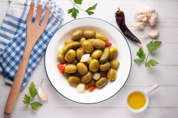 White plate with grilled olives, onions, peppers, and pickles. Overhead view of the table.