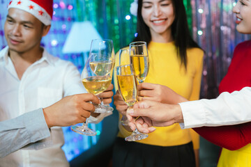 Group of friends wearing Santa hats raising glasses of champagne, celebrating Christmas or New Year together with joy and smiles.