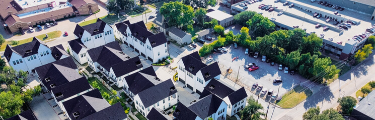 Panorama aerial view townhomes near Cooper Street, Arlington, Texas with rooftop ramp garage, commercial buildings reinforce accessibility and urban layering near university and retail zones