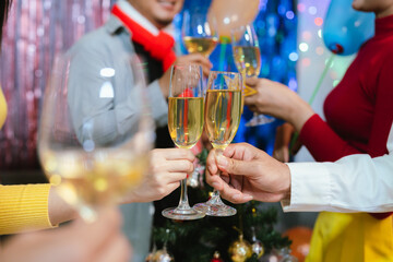 Group of friends wearing Santa hats raising glasses of champagne, celebrating Christmas or New Year together with joy and smiles.