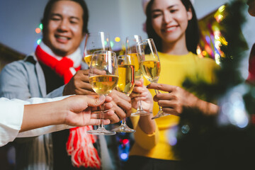 Group of friends wearing Santa hats raising glasses of champagne, celebrating Christmas or New Year together with joy and smiles.