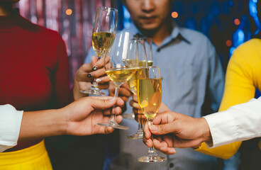 Group of friends wearing Santa hats raising glasses of champagne, celebrating Christmas or New Year together with joy and smiles.