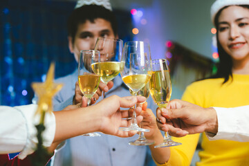 Group of friends wearing Santa hats raising glasses of champagne, celebrating Christmas or New Year together with joy and smiles.