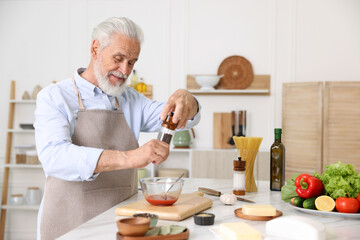 Elderly man cooking at white marble table in kitchen