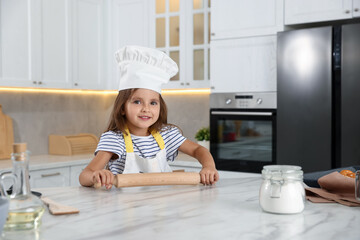 Choice of profession. Little girl with rolling pin pretending to be chef in kitchen