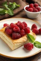 Yummy puff pastry with raspberries on wooden table, closeup