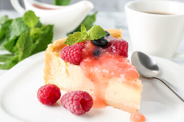 Piece of tasty cheesecake with berries and sauce on table, closeup