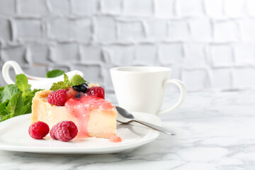 Piece of tasty cheesecake with berries and sauce served on white marble table, closeup. Space for text