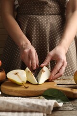 Woman cutting fresh pears at wooden table, closeup