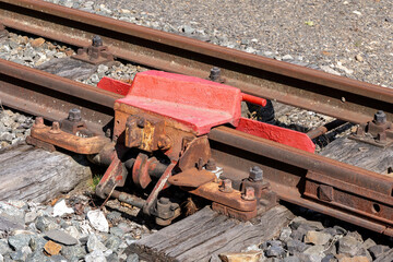 red railway buffer stop on rusty train track with wooden sleepers and gravel