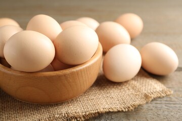 Raw chicken eggs in bowl on wooden table, closeup